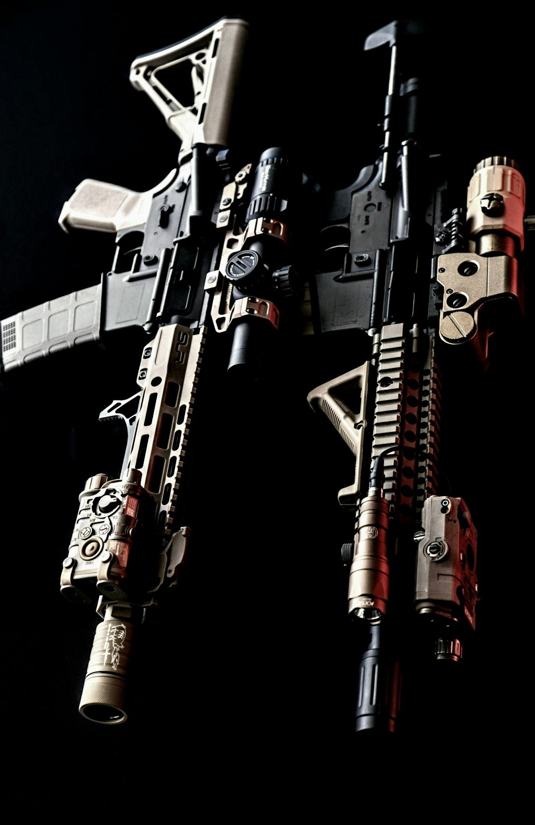 Two tactical rifles equipped with scopes and accessories rest together.